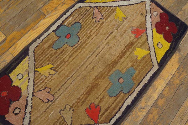 A rectangular, textured rug with colorful floral motifs on a brown background rests on hardwood flooring.