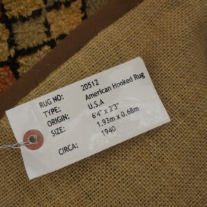 Reverse side view showing a burlap backing, brown binding, and multicolor high-pile hooked rug border.