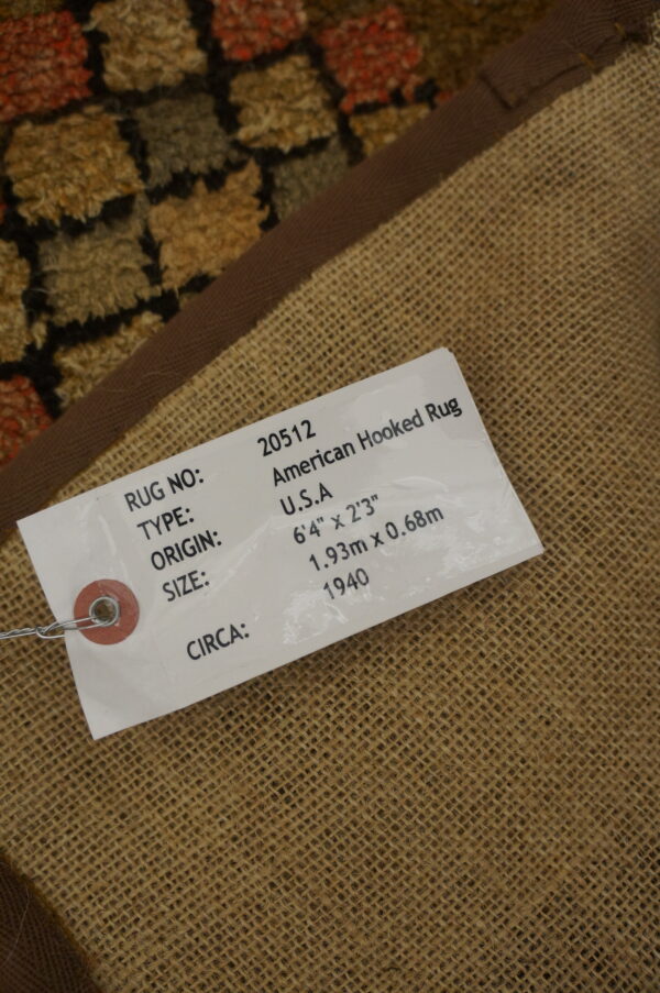 Reverse side view showing a burlap backing, brown binding, and multicolor high-pile hooked rug border.