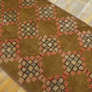 Olive green runner rug featuring a diamond lattice pattern in coral, gray, and tan on rustic wood flooring.