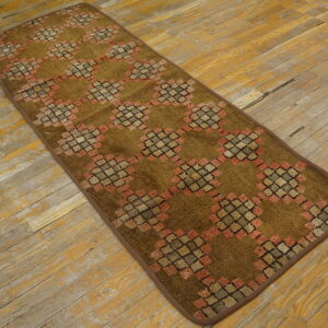 Olive-brown runner rug with a geometric lattice design sits on distressed yellow and gray wood flooring.