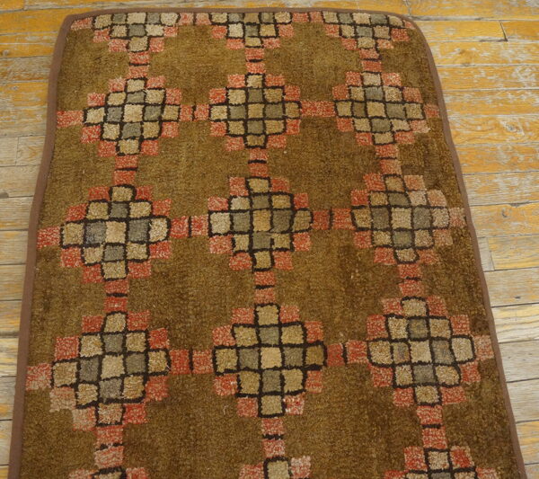 Brown shag runner featuring a repeating geometric block pattern in rust, cream, and gray on distressed wood floors.