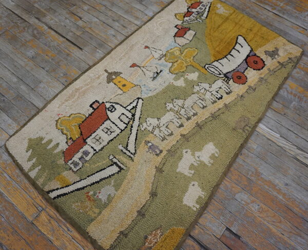 Beige, green, and yellow hooked rug with a colorful countryside motif on distressed wood flooring.