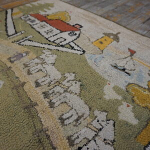 Loop-pile scenic rug with green, cream, and orange house pattern visible on distressed wood flooring.