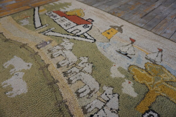 Loop-pile scenic rug with green, cream, and orange house pattern visible on distressed wood flooring.
