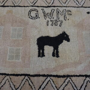 High-pile rug featuring a black horse, stylized pale houses, the initials G.W.Mc., and the date 1787.