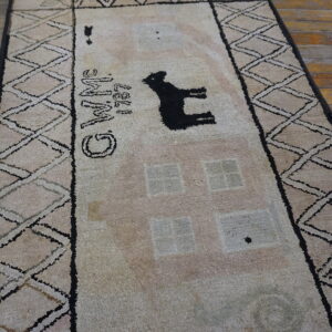 High-pile beige rug with a black animal silhouette and "WINE" text on distressed wood flooring.