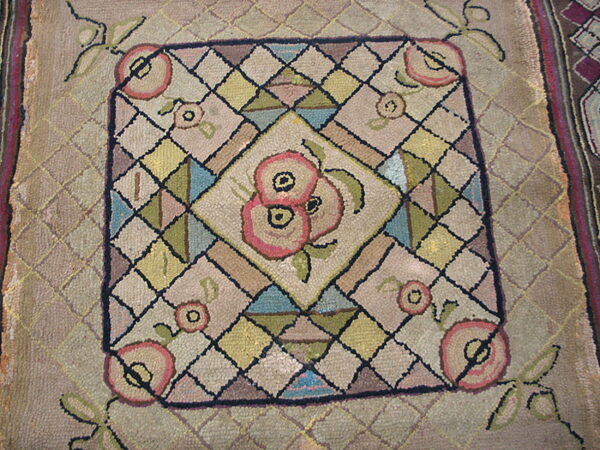 Textured rug with a central pink floral pattern inside a multicolored geometric diamond grid.