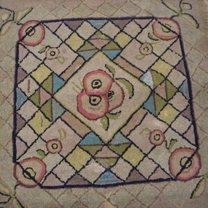 Textured rug detail showing pink florals and geometric diamonds in muted beige, green, and blue tones.