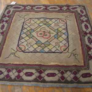 Tan rug with a central multi-color fruit motif and wide geometric borders on wood flooring.