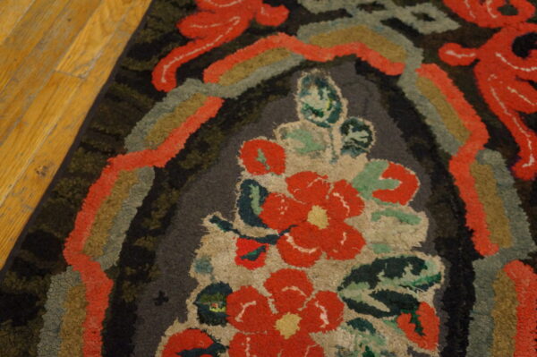 Textured loop pile rug featuring a bold coral and green floral design against dark charcoal on wood floors.
