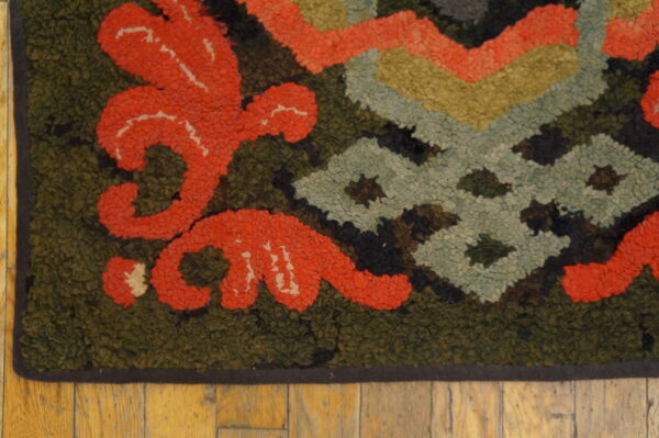 Textured rug corner showing stylized coral floral motifs and geometric designs on olive green.