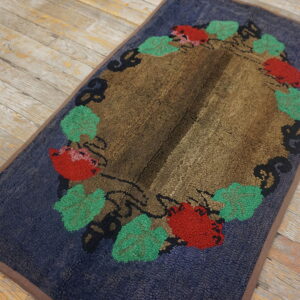 Textured navy and brown rug with a wreath of red and green foliage displayed on distressed plank flooring.