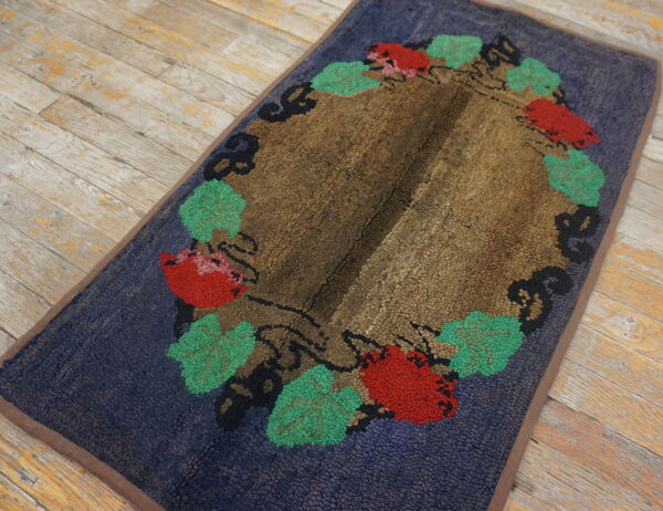 Textured navy and brown rug with a wreath of red and green foliage displayed on distressed plank flooring.