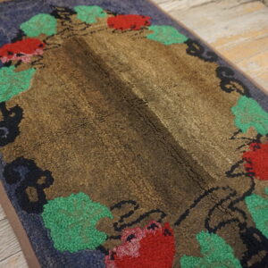 Textured rug with a brown center, blue field, and red and green floral pattern on wood floor.