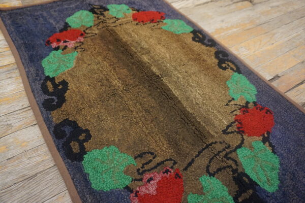 Textured rug with a brown center, blue field, and red and green floral pattern on wood floor.