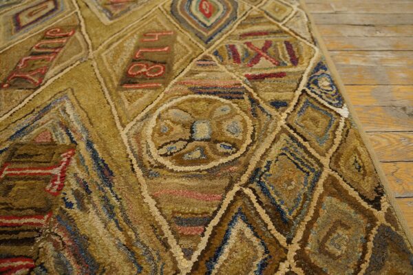 Highly textured gold and brown rug with red numbers and geometric shapes on distressed wood floor.