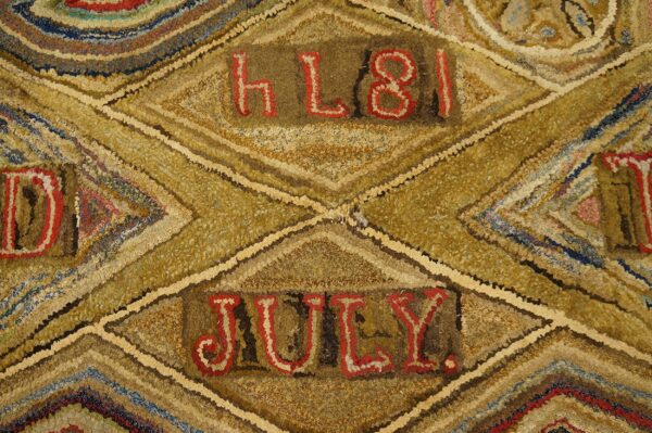 High-textured rug detail showing gold, brown, and blue diamond patterns with red letters spelling "july" and "h l 8 1".