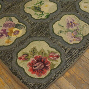Textured rug with scalloped medallions containing multicolored flowers resting on weathered wood flooring.