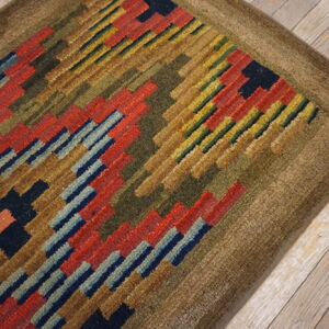 High-pile rug with geometric blocks of red, navy, and olive green on light wood floors.