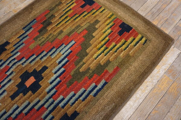 High-pile rug with geometric blocks of red, navy, and olive green on light wood floors.