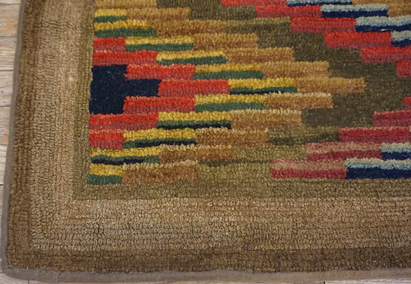 Hooked-style rug featuring a multi-colored geometric pattern against a textured solid brown border on wood floor.