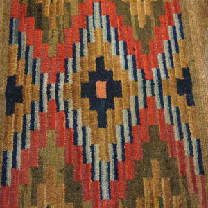 Shaggy runner with colorful stepped geometric designs in red, blue, and gold on light wood planks.