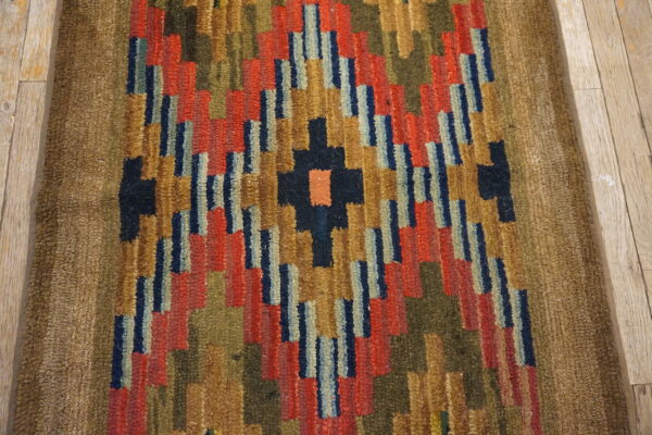 Shaggy runner with colorful stepped geometric designs in red, blue, and gold on light wood planks.