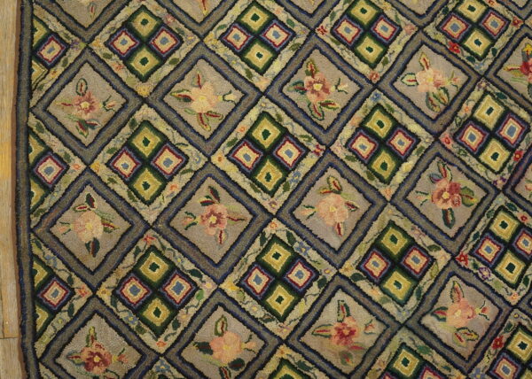 Textured hooked rug featuring a gray and green diamond lattice pattern with alternating floral and geometric motifs.