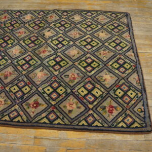 A muted gray rug with alternating geometric and floral diamond patterns rests on worn wood flooring.
