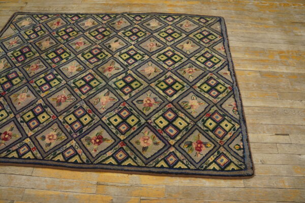 A muted gray rug with alternating geometric and floral diamond patterns rests on worn wood flooring.