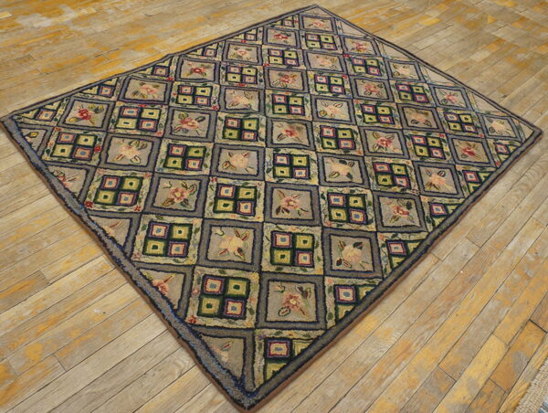 Textured gray and multicolored rug with alternating floral and windowpane squares laid diagonally on distressed wood floor.