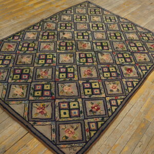 Multicolor hooked rug with a checkerboard pattern of flowers and geometric blocks on wood plank floors.