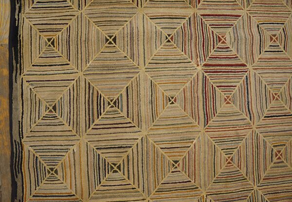 Geometric hooked rug featuring nested squares filled with varied vertical and horizontal stripes in many earthy colors.