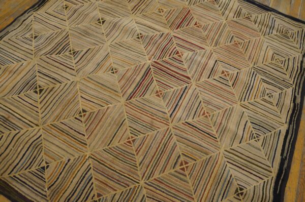 Muted multi-colored striped rug with a repeating geometric diamond pattern on light wood floors.