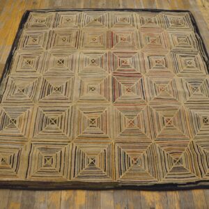 Textured multicolored rug featuring a pattern of concentric squares on worn yellow-gold wooden flooring.