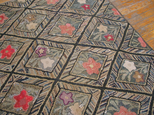 Highly textured rug with floral diamonds in red, pink, and beige on a green and blue background, resting on wood flooring.