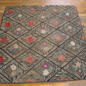 Muted, multicolored hooked rug with a floral diamond pattern displayed on plank hardwood floor.