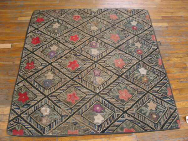 Muted, multicolored hooked rug with a floral diamond pattern displayed on plank hardwood floor.