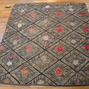 Textured rug featuring a dark diamond lattice with red, purple, and pale floral motifs on hardwood planks.
