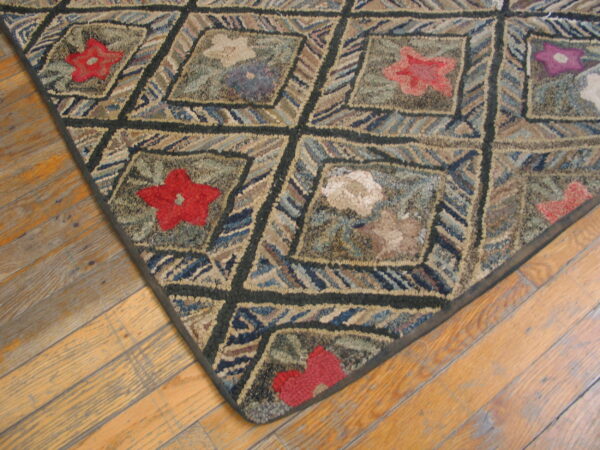 Coarse-textured rug featuring a dark diamond grid, multicolored stripes, and red floral motifs on wood flooring.