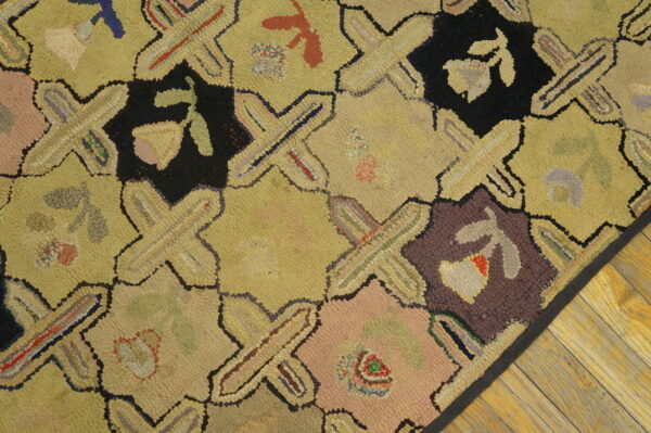 Yellow, black, and multicolored hooked rug with a geometric lattice design sits on light wood flooring.
