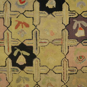 Tan, pink, black, and blue looped rug featuring a geometric grid pattern on rustic hardwood planks.