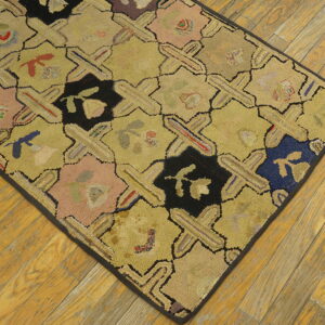 Geometric hooked rug featuring yellow crosses and colorful floral designs on distressed wood floor.