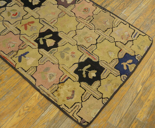 Geometric hooked rug featuring yellow crosses and colorful floral designs on distressed wood floor.
