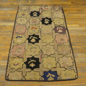 Tan, pink, black, and blue looped rug featuring a geometric grid pattern on rustic hardwood planks.