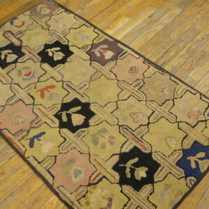 A hooked runner rug with a yellow background and a black, pink, and blue octagonal lattice pattern lies on wooden flooring.