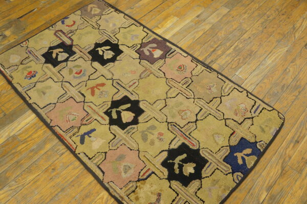 A hooked runner rug with a yellow background and a black, pink, and blue octagonal lattice pattern lies on wooden flooring.