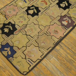 Low-pile hooked rug with multicolored geometric patches and crosses resting on rustic wood plank flooring.