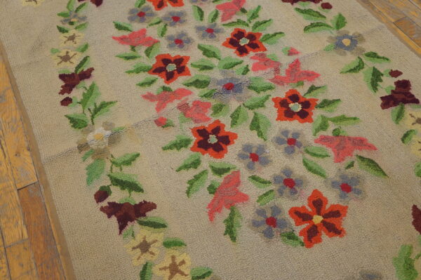 Low-pile beige hooked rug featuring a colorful vertical floral garland on distressed wooden flooring.